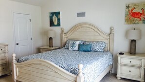 Een slaapkamer met een bed, twee nachtkastjes, een deur en decoraties aan de muur.