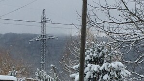 A snowy landscape with a utility pole, a fence, and a building in the background. - hat                  (Yaremche)
