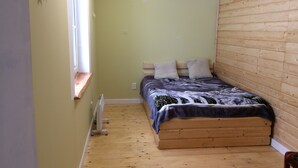 A small, cozy room with a wooden bed, a window with a wooden shelf, and a radiator on the floor. - hat                  (Yaremche)