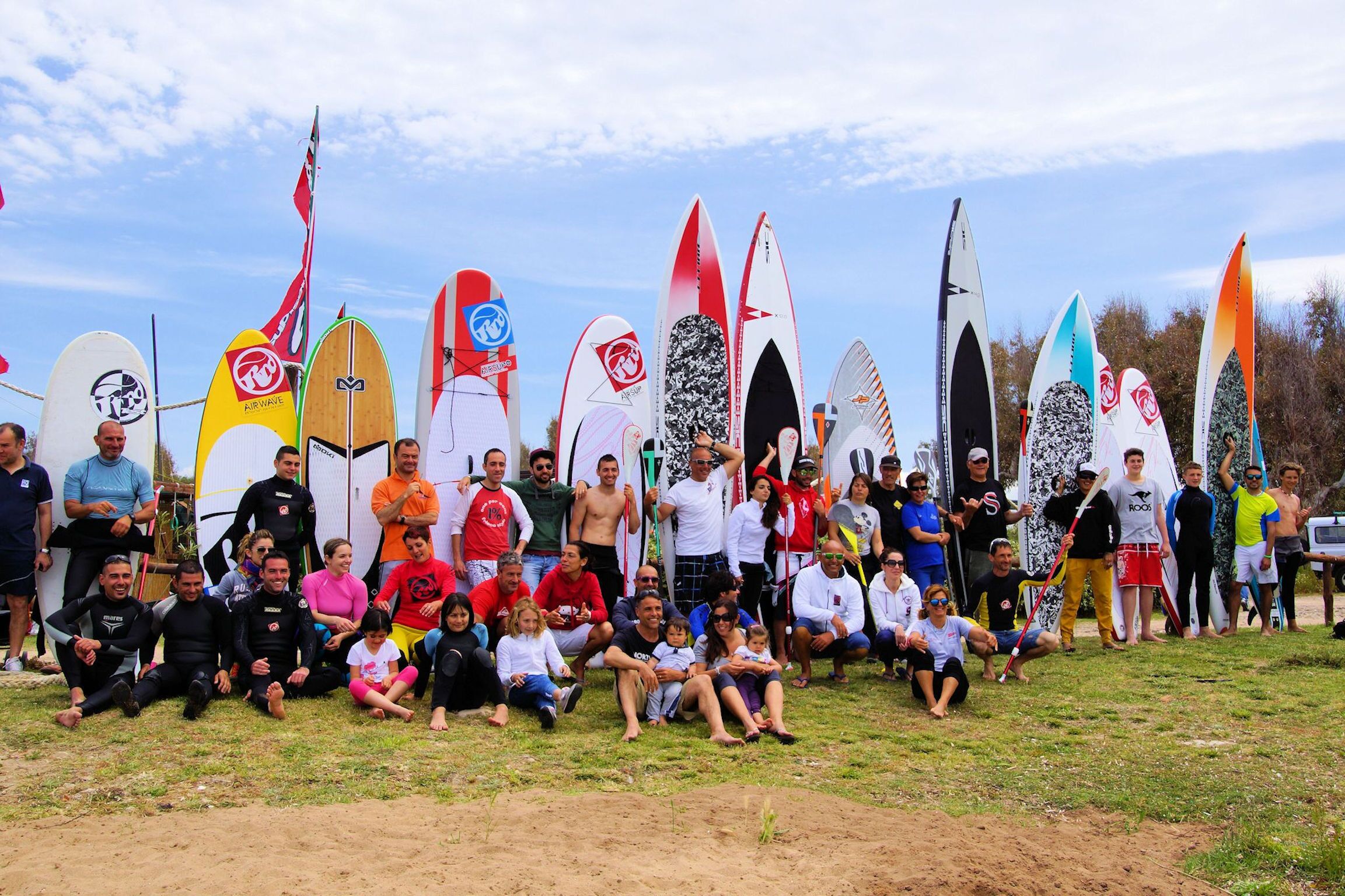 Un grupo de personas con tablas de surf en un espacio al aire libre con césped.