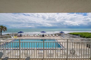 A pool area with a view of the ocean, a fenced deck, and lounge chairs. - Oceanfront 2BR Condo 2nd Floor Balcony Overlooking Pool, Unit 201 (Indian Harbour Beach)