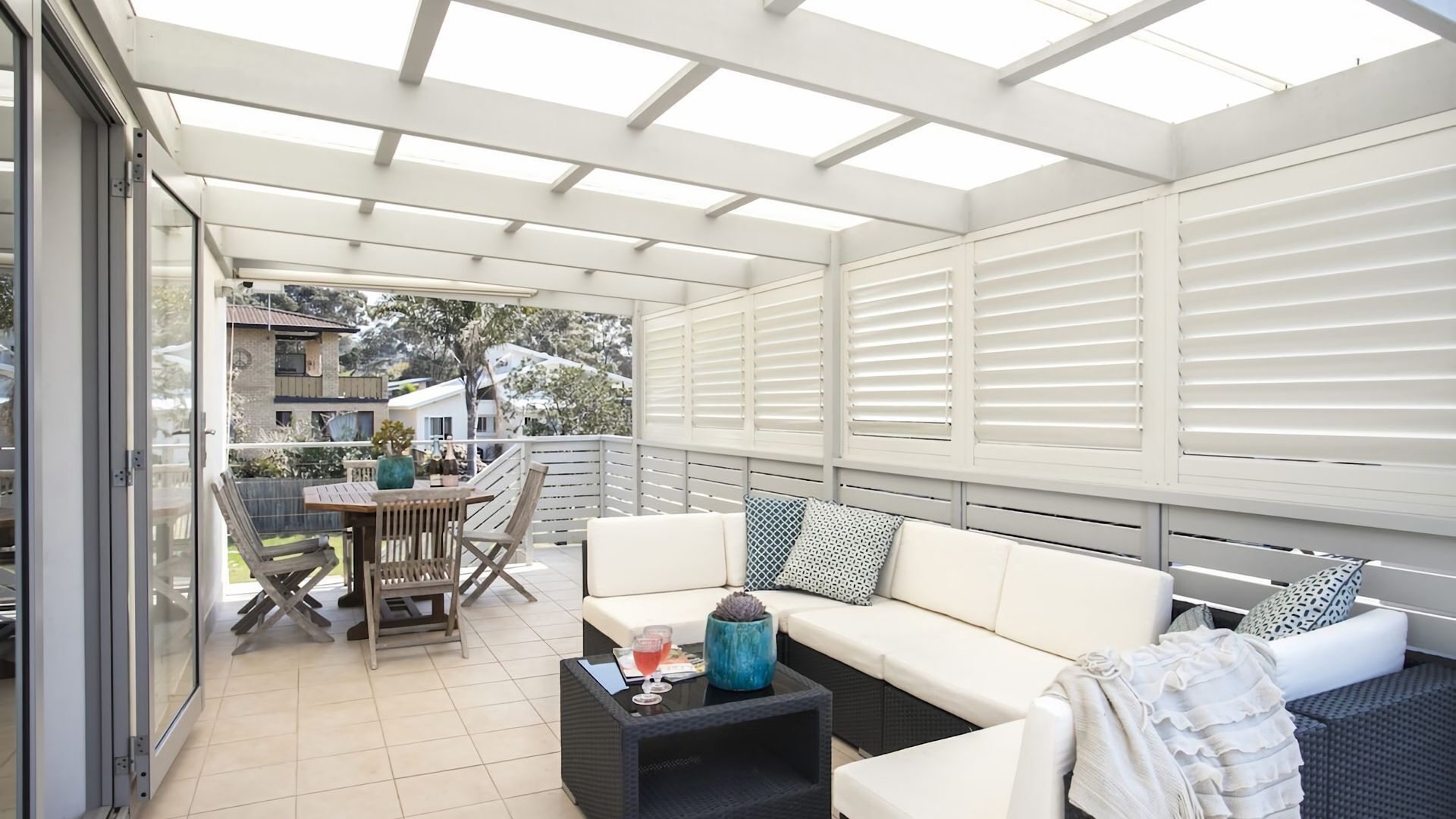 A covered patio area with a sofa, chairs, and a table.