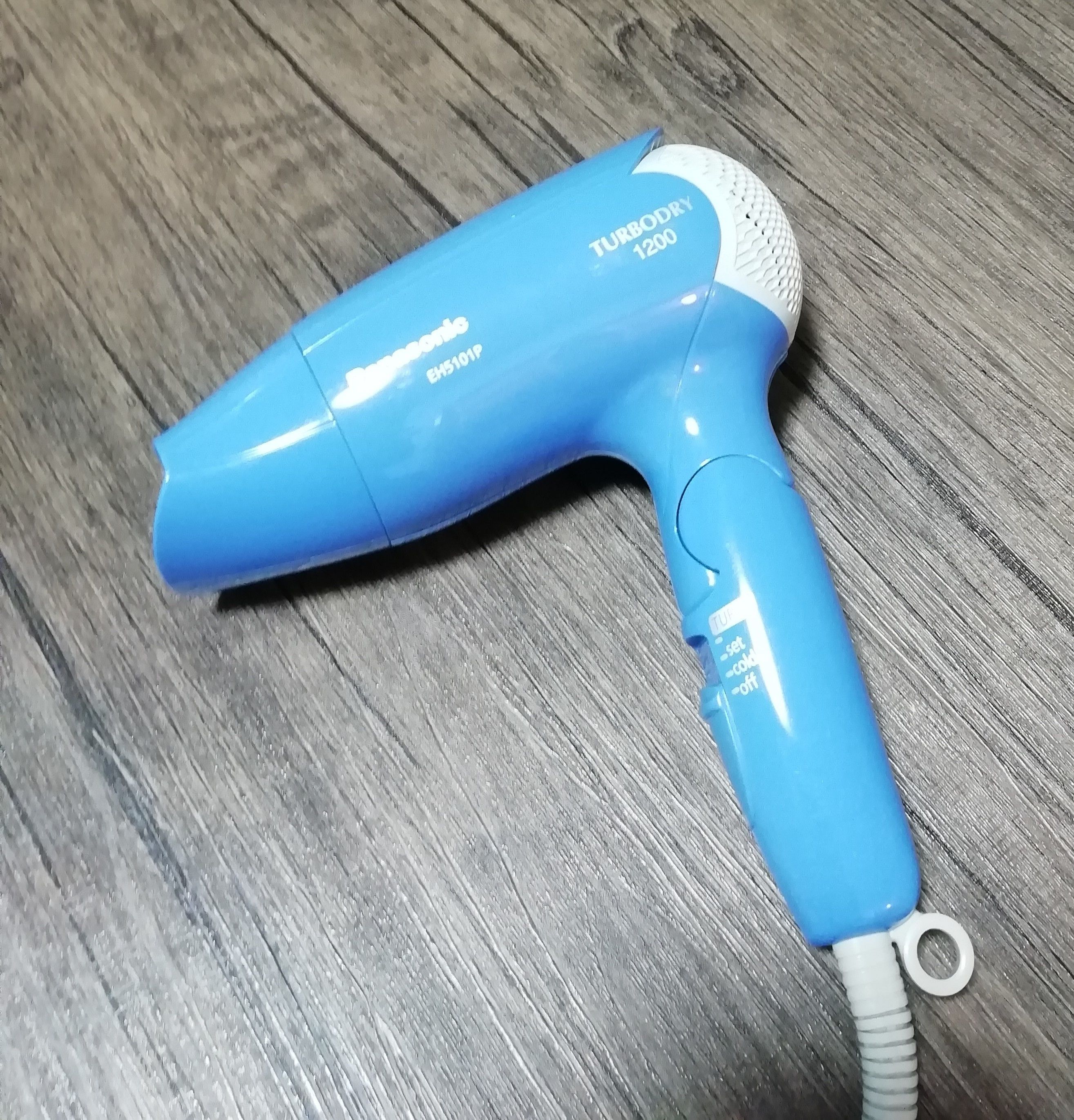 Un sèche-cheveux bleu, modèle EH5101P, posé sur une surface en bois.