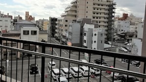 A multi-story building with a prominent tower, surrounded by other residential buildings. - Apartment near Tram in Okayama (Okayama)