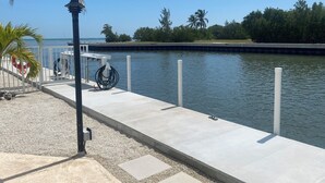 A waterfront dock with a lifebuoy, a lamp post, and a hose. - Cozy Home!!!! (Marathon)