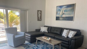 A modern living room with a sectional sofa, a single armchair, a coffee table, and a patterned rug. - Cozy Home!!!! (Marathon)