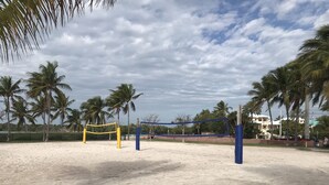 A beach volleyball court with a net, palm trees, and a building in the background. - Cozy Home!!!! (Marathon)