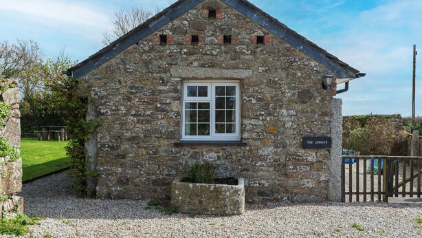Un bâtiment en pierre avec un toit à deux versants, une fenêtre à cadre blanc et une enseigne indiquant « THE LINHAYE ».