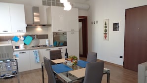 Une cuisine moderne avec des meubles blancs, une table à manger avec des chaises et un petit coin repas.