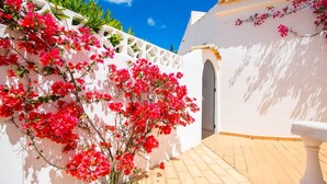 A white building with a tiled patio and a doorway. - Casa Alegria · This villa is perfect for a family (Lagoa)