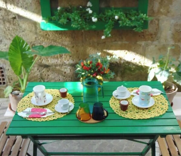 A green table set with white cups, saucers, and a yellow doily.