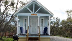 A small, light blue cabin with a porch and a sign reading "Coast Cake". - Coast Oak -Beautiful New Tiny Cottage - Perfect Family Getaway (Aransas Pass)