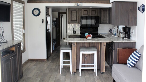 A compact kitchen with a central island, wooden cabinets, and a microwave. - Coast Oak -Beautiful New Tiny Cottage - Perfect Family Getaway (Aransas Pass)