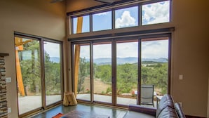 Amplia habitación con ventanas grandes que ofrecen vistas a un paisaje montañoso.