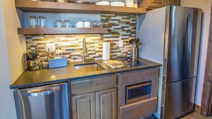 Una cocina moderna con electrodomésticos de acero inoxidable, armarios de madera y salpicadero de piedra.