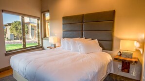 Una cama grande con ropa de cama blanca, un cabecero y dos lámparas de noche.