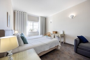 Een hotelkamer met twee bedden, een bureau, een stoel, een lamp en uitzicht op de omgeving.