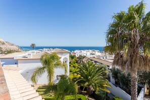 Une ville côtière aux bâtiments blancs, sous un ciel d’un bleu limpide, offrant une vue sur la mer.