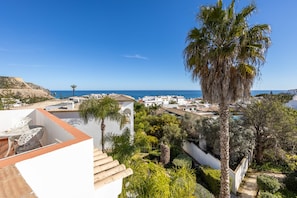 A coastal residential area with white buildings, a palm tree, and a clear view of the sea.