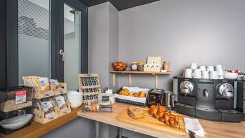 Un buffet de petit-déjeuner comprenant divers aliments, des machines à café et des récipients de rangement.