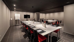 A conference room with a long table, chairs, a whiteboard, and a flat-screen TV. - Hotel Artist (Biel)