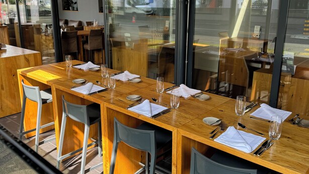 A restaurant with wooden tables and chairs, large windows, and a view of the street. - Hotel Artist (Biel)