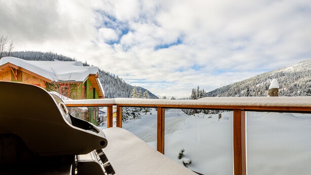 A snow-covered landscape with a wooden deck and a view of a cabin.