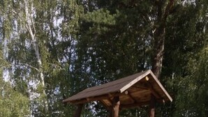 Eine hölzerne Spielkonstruktion mit Rutschen und Kletterelementen in einem Sandspielbereich.