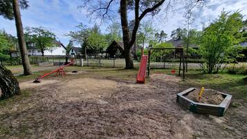 Explore the playground area with a slide and swing set amidst lush surroundings.