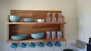 A wooden shelf with stacked plates and glasses.