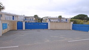 Un parking clos, doté de portails bleus, et un immeuble avec des balcons.