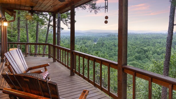 Une terrasse en bois avec deux chaises Adirondack et une suspension lumineuse.
