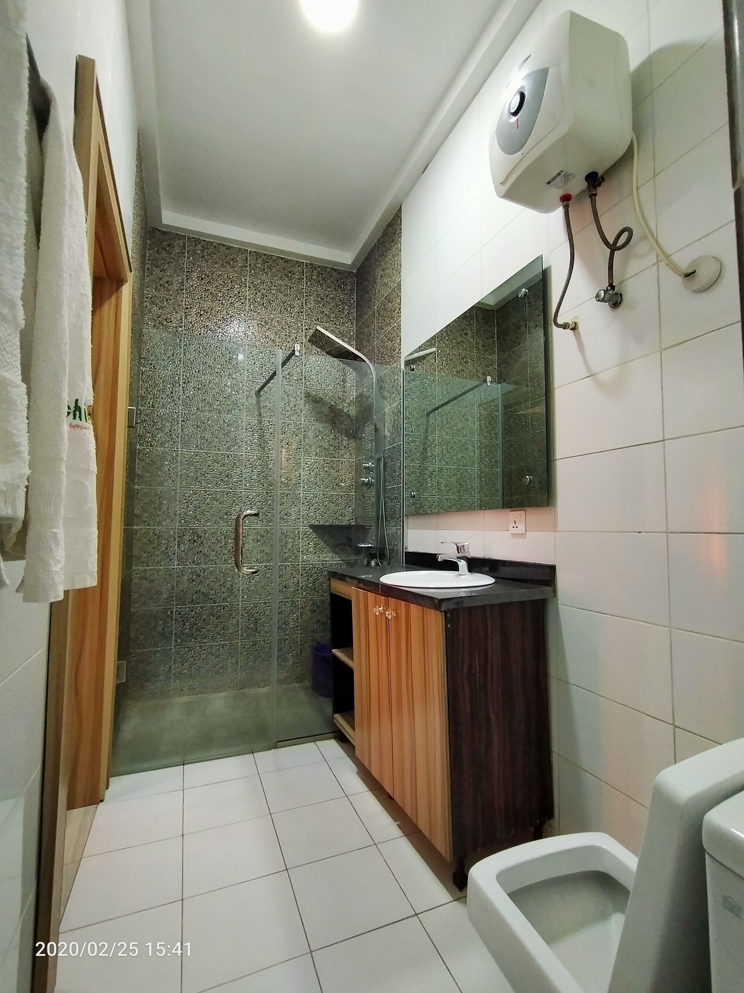A modern bathroom with a glass-enclosed shower, a white sink, and a toilet.