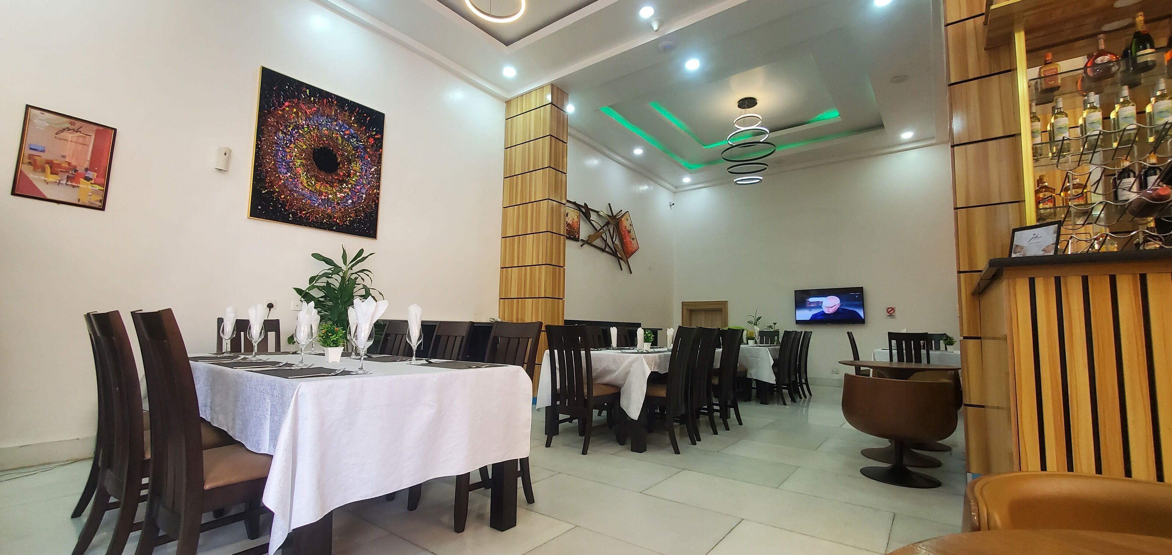 A restaurant with multiple dining tables, chairs, and a TV screen on the wall.