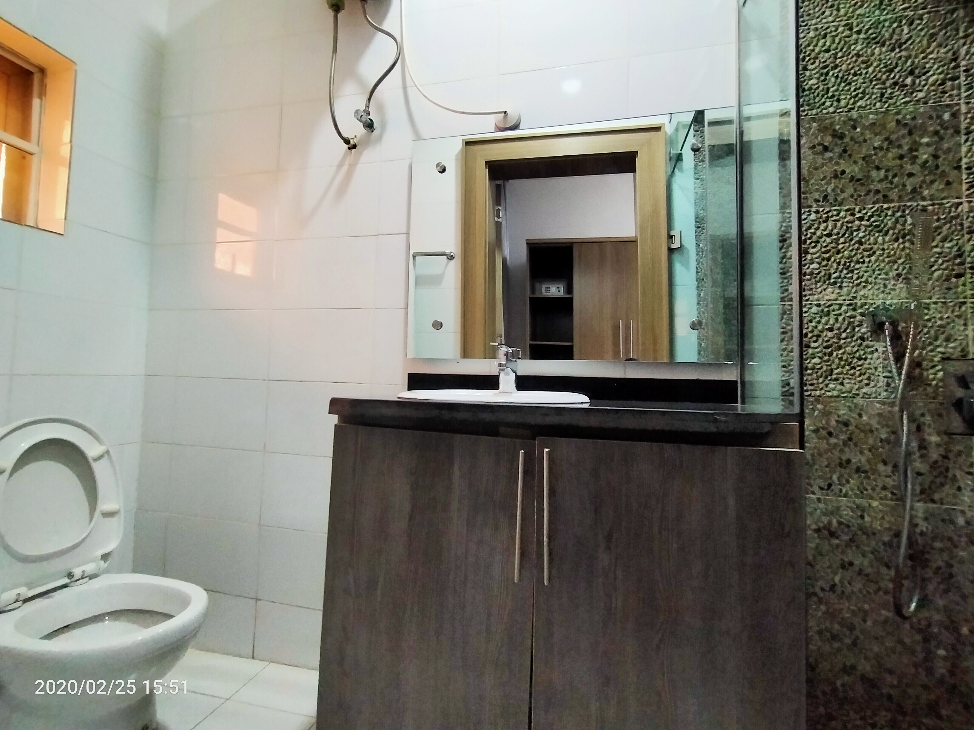 Un baño con inodoro, lavamanos con espejo y zona de ducha.