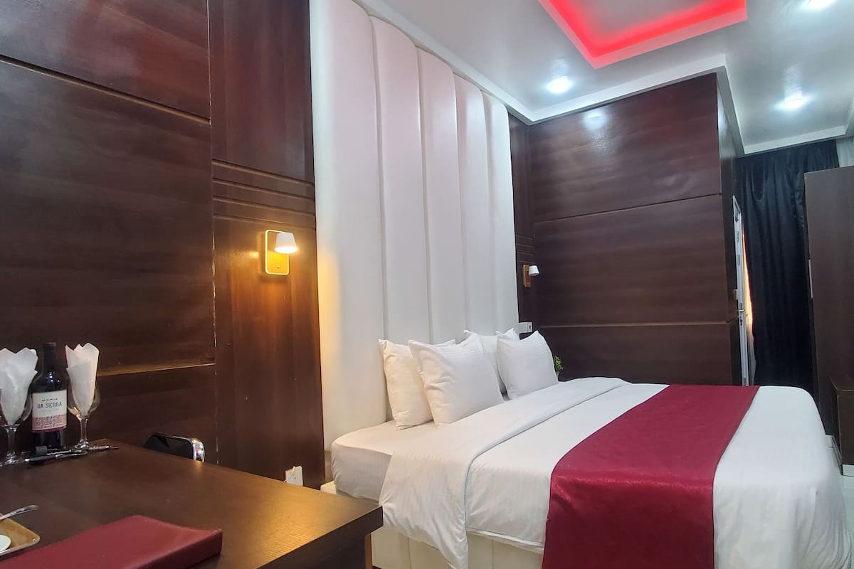 A hotel room with a bed, bedside table, and a TV mounted on the wall.
