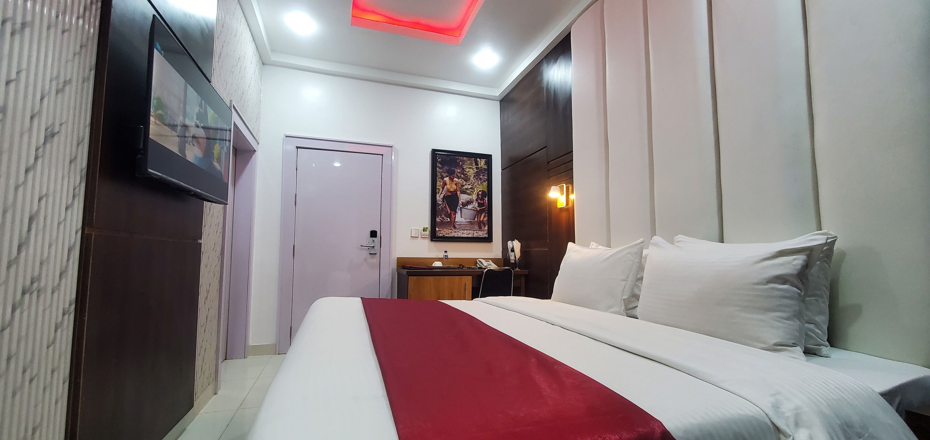A hotel room with a bed, a desk, and a door.