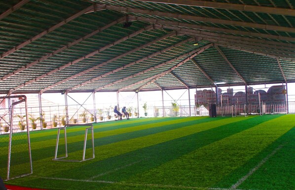 An indoor sports facility with artificial turf, goalposts, and a covered roof structure. - Dalchifit Suites (Abuja)