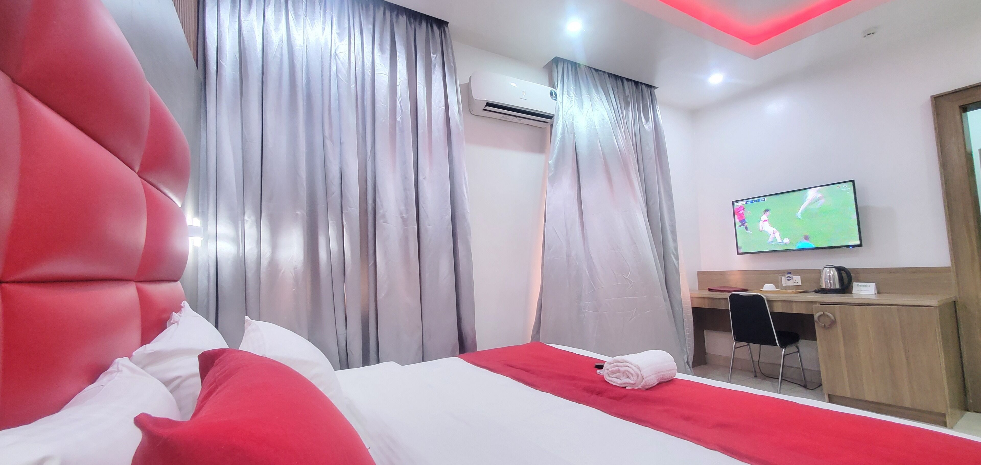 A hotel room with a large bed, a desk, a television, and curtains.