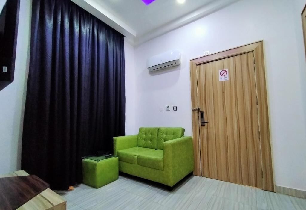 A room with a green sofa, a wooden door, and a black curtain.