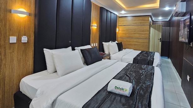 Una moderna camera d'hotel con un letto grande, pannelli in legno e illuminazione integrata.