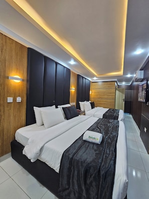 A modern hotel room with a large bed, wooden paneling, and built-in lighting. - Dalchifit Suites (Abuja)