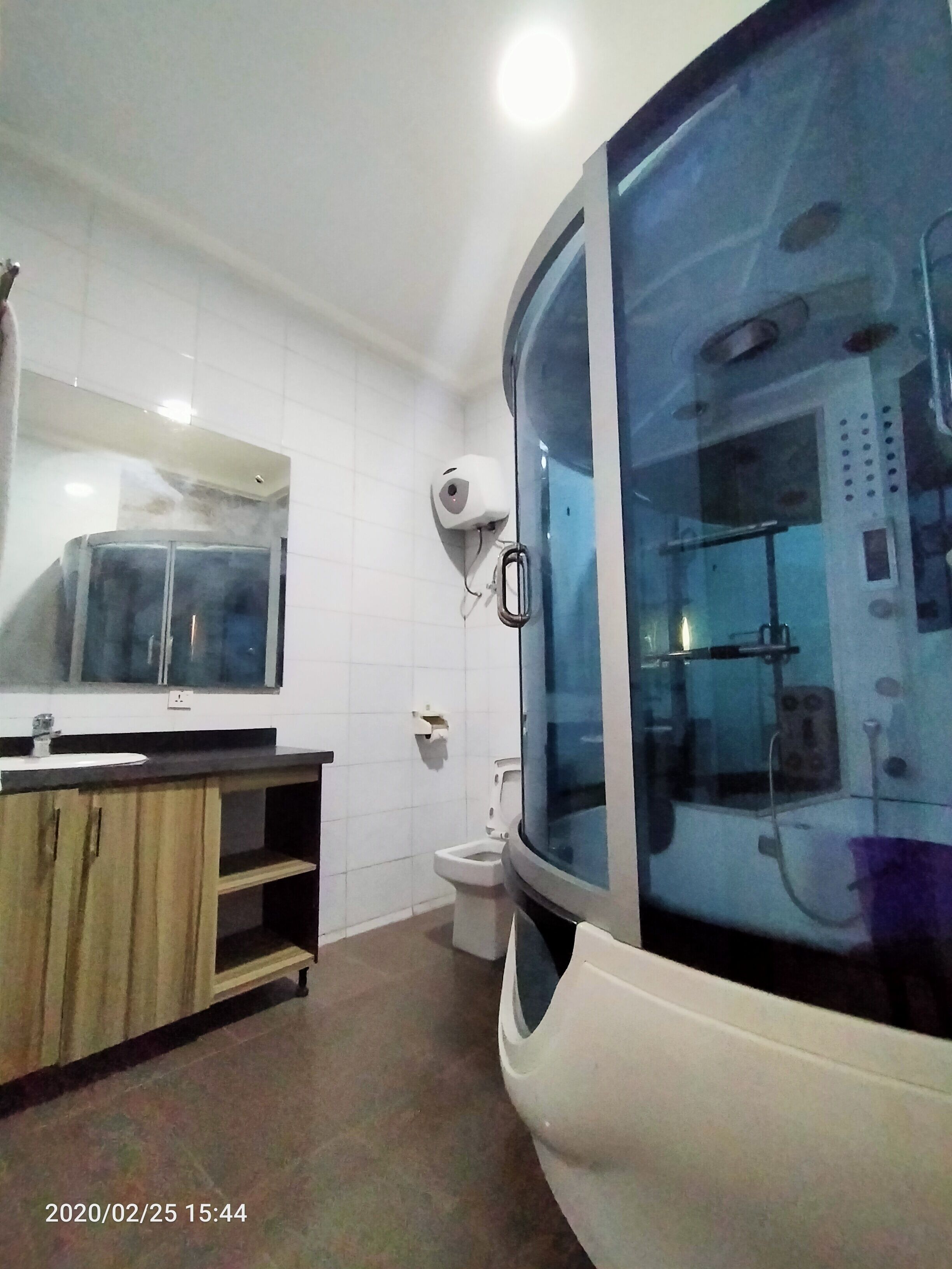 A modern bathroom with a glass-enclosed shower, a toilet, and a vanity with a mirror.