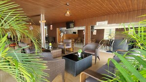 Un'area lounge moderna con mobili in vimini, una televisione a schermo piatto e un ventilatore a soffitto.