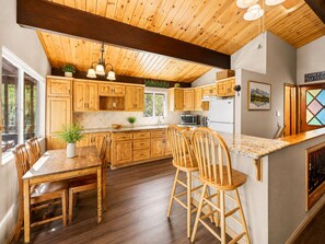 A kitchen with wooden cabinets, a dining table, chairs, and a bar area.