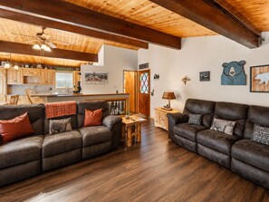 A cozy living room with two leather sofas, a wooden coffee table, and a kitchen in the background.