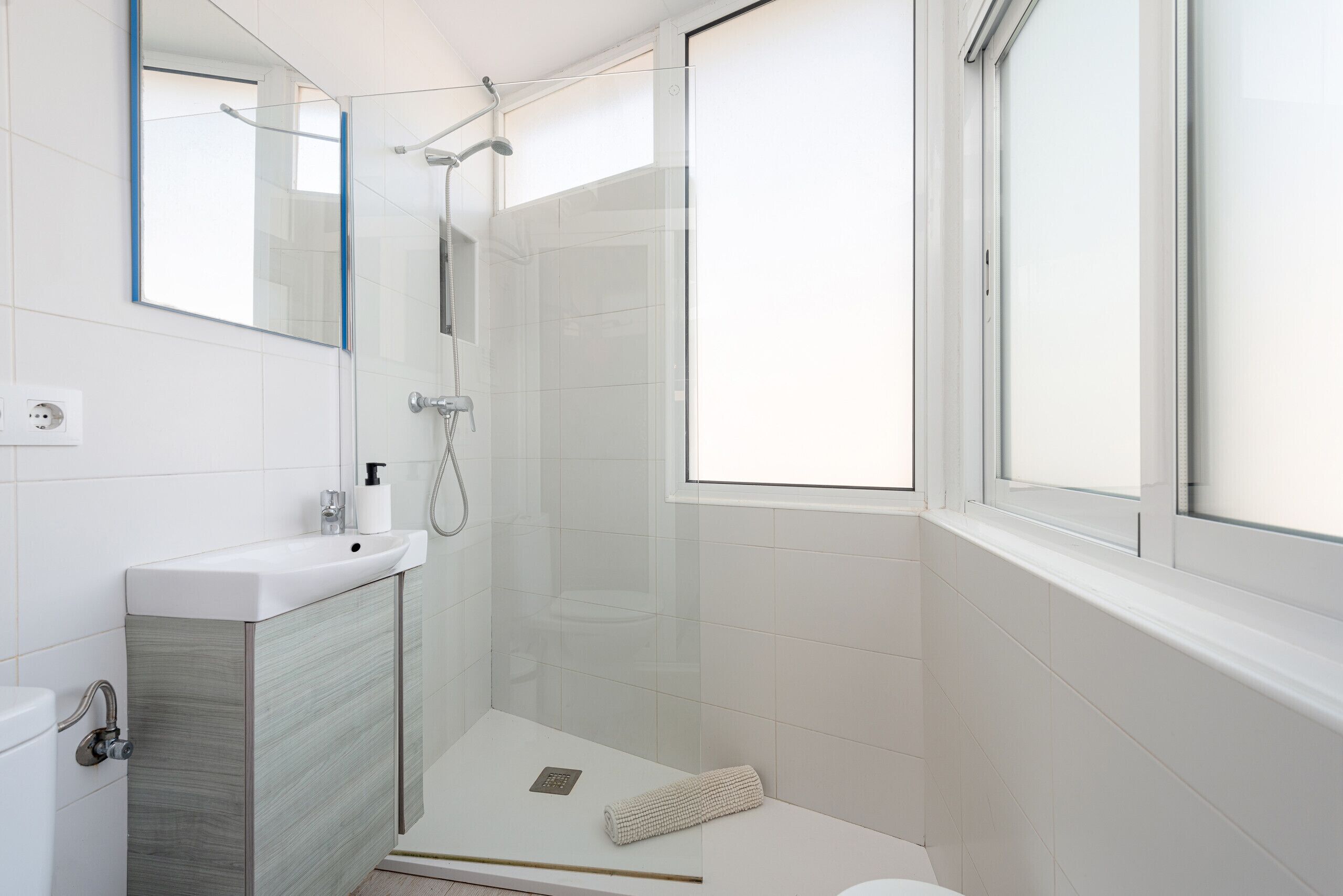 A modern bathroom with a glass-enclosed shower, a white sink, and a toilet.