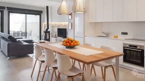 Eine moderne Küche mit weißen Schränken, einem Holztisch und einer Obstschale.