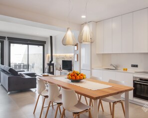 Una cocina moderna con armarios blancos, una mesa de comedor de madera y un frutero.