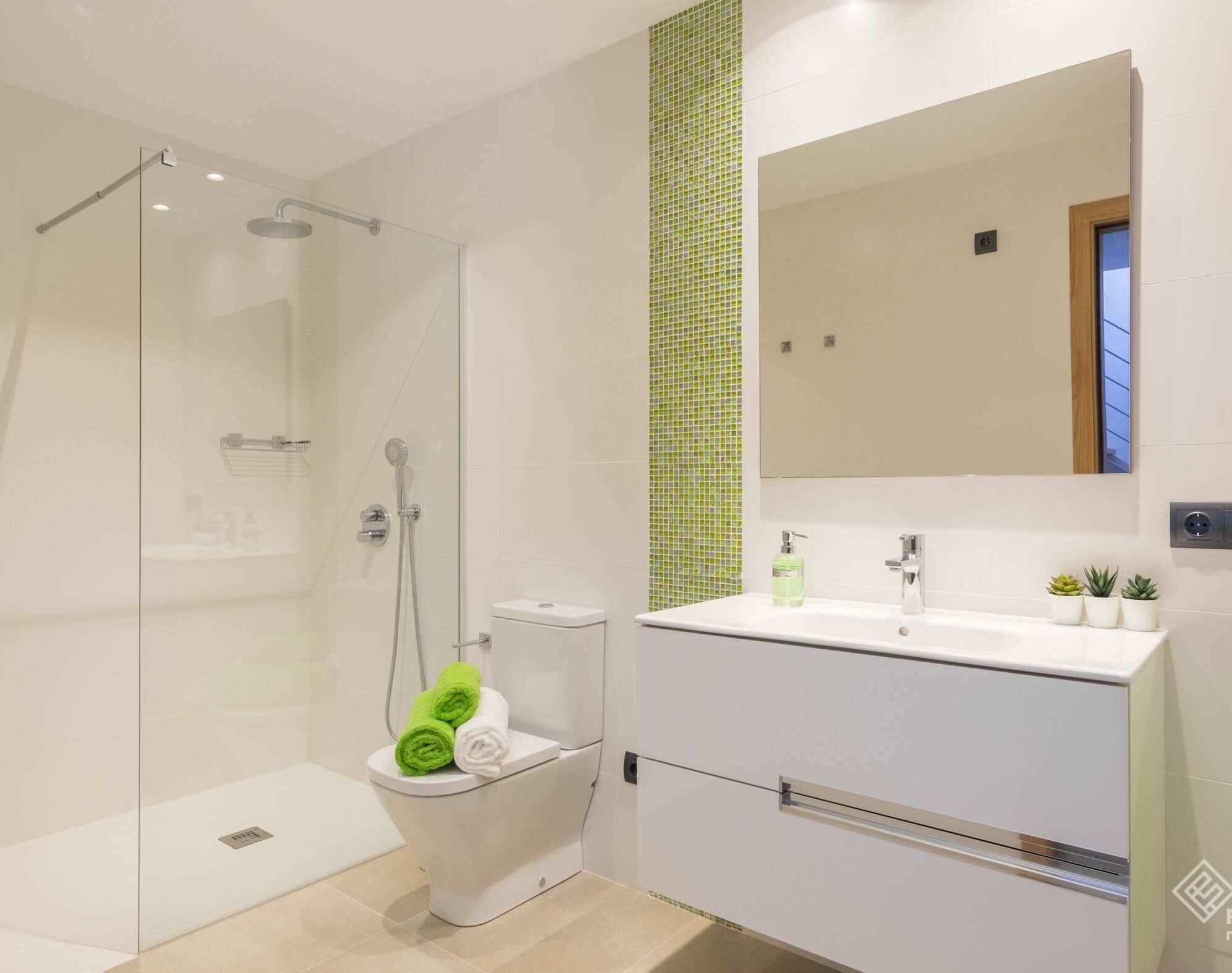 Une salle de bain moderne avec une douche à parois de verre, des toilettes, un lavabo avec un miroir et une petite plante en pot posée sur le comptoir.